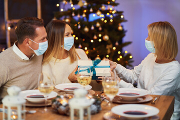 Friends celebrating christmas party wearing mask.