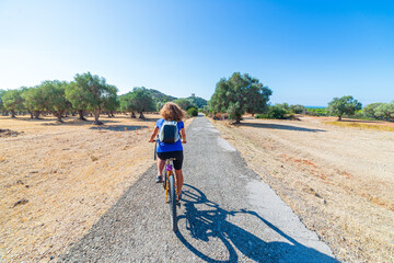 Woman riding MTB in Maremma nature reserve, Tuscany, Italy. Cycling among extensive pine forest olive trees and green woodland in natural park, dramatic coast