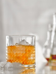 A glass of whiskey with ice on the table in a high key