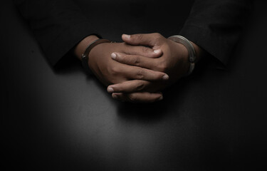 Obraz premium A businessman in a black suit puts handcuffs on the table and the black table. Corruption, bribery, illegal transactions