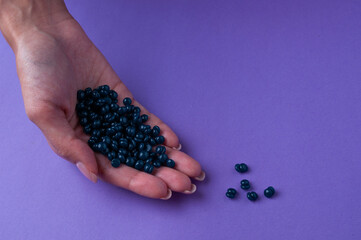 Girl's hand hold granules of wax for depilation