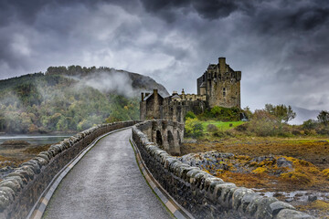 Moody autumn view of the Eilean Donan Castle in the Highlands of Scotland with misty mountains and...