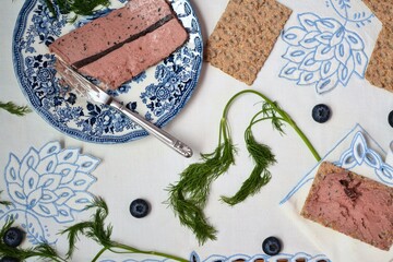 Terrine or pate with blueberries surrounded by toast on an embroidered tablecloth