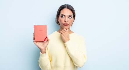 pretty hispanic woman thinking, feeling doubtful and confused. agenda concept