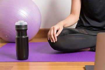 Young woman watching live online pilates group class tutorial on laptop computer at home, doing yoga workout meditation online.