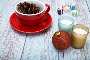 Christmas table decorations with scented candles and a red coffee cup on pale bluewooden background.