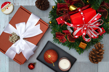 Christmas dinner table decorations with a cup of coffee, sugar coated biscuits, scented candle and red gift boxes.