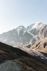Snow-capped mountains of the caucasus close-up. On the Sunset. Brown soil and no trees. Vertical photo.