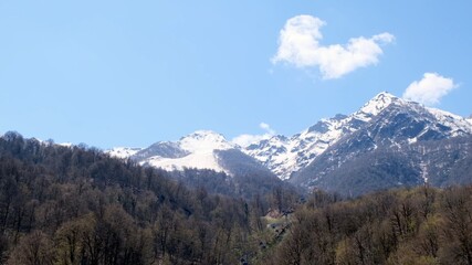 beautiful landscape of snow-capped mountains with white clouds on blue sky on a sunny day at Krasnaya Polyana in Sochi, Russia. Famous ski resort