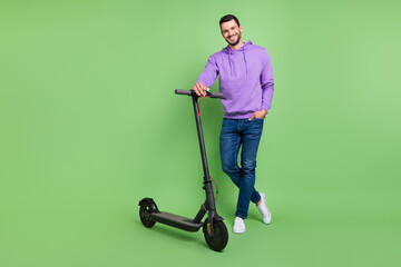Full length photo of young cheerful man happy positive smile walk electric scooter isolated over...