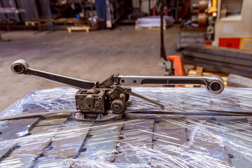 Manual tension strapping machine. A device for tensioning a metal strip. Tool for strapping boxes and pallets.