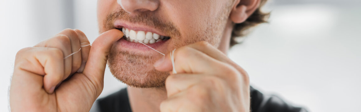 Cropped view of man cleaning teeth with dental floss at home, banner