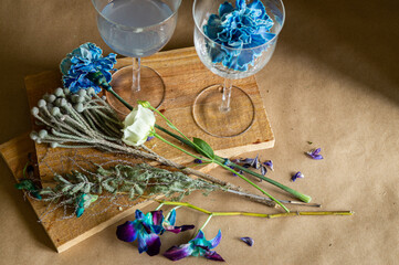 Fototapeta na wymiar two glasses for wine with alcohol and a bouquet of blue and blue flowers on wooden boards