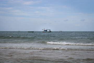 The fishing boat floats in the middle of the sea in the evening.
