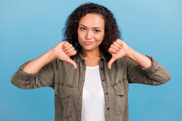 Portrait of attractive dissatisfied wavy-haired girl showing double thumb down isolated over bright...