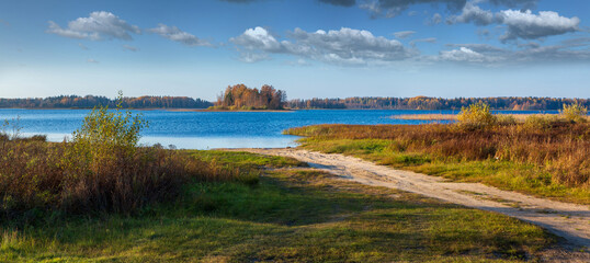 Autumn panorama with sandy road and blue lake