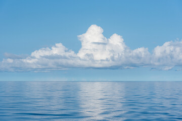 Beautiful blue sky, with fluffy clouds over the calm Pacific Ocean. 