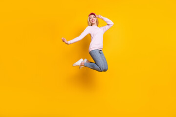 Fototapeta na wymiar Photo of charming carefree young lady wear pink sweater headwear smiling jumping high isolated yellow color background