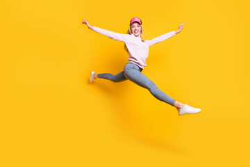 Fototapeta na wymiar Photo of carefree shiny young lady wear pink sweater headwear smiling jumping high isolated yellow color background