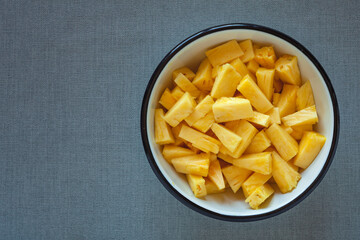 Pineapple chunks top view. Bowl full of fresh tomato cut into pieces.