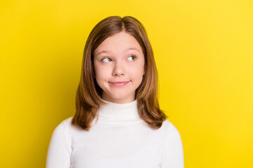 Photo of young attractive little girl happy positive smile dream think look empty space isolated over yellow color background