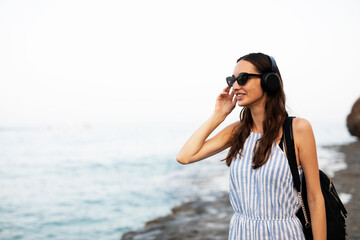 Hot woman relaxing on the sandy beach. Beautiful woman with headphones listening the music.