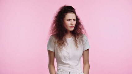 displeased young woman in white t-shirt looking away isolated on pink