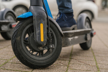 Obraz premium Close-up of a foot on an electric scooter parked on the sidewalk in the city. Ready to use. Urban transport