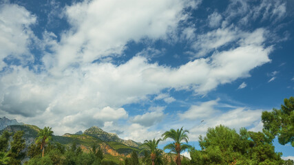 Fototapeta na wymiar beautiful clouds against blue sky, mediterranean coast with mountains, palms and pines