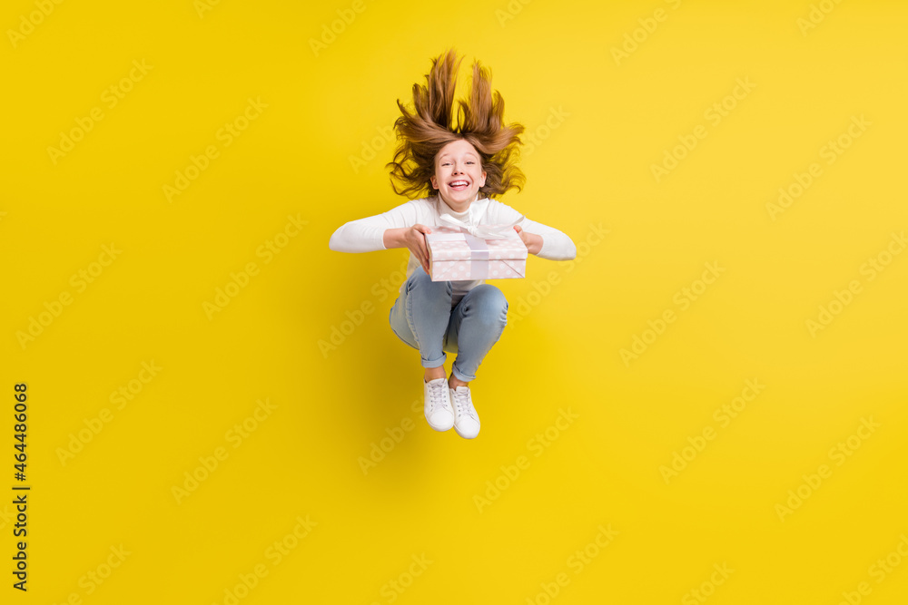 Sticker Full body photo of happy brunette young little girl jump hair fly hold present box isolated on yellow color background