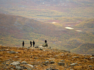 Human silhouettes on top of mountain against distant colorful landscape in fall