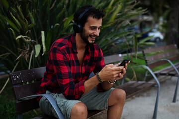 Young man listening to music. Urban fashion man with headphones enjoying the city.