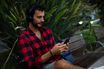 Young man listening to music. Urban fashion man with headphones enjoying the city.