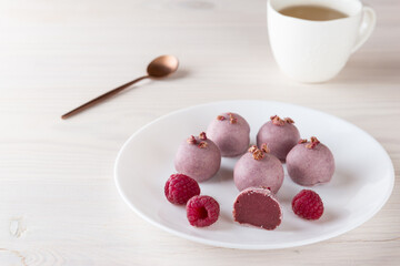 Sweets with raspberries in pink chocolate on a white plate. Sugar, gluten and lactose free.
