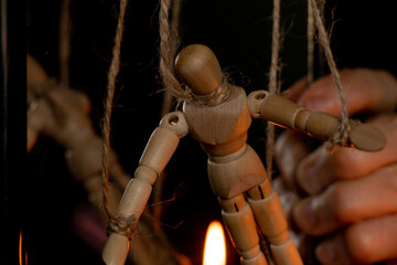 a wooden man on ropes tied to a man's hand, manipulation of people and slavery, free will, power