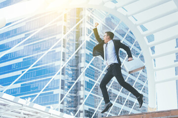 Successful businessman celebrating his victory with jump up in feeling happy on cityscape background.