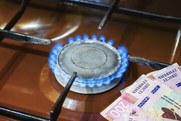Ukrainian hryvnia currency and old gas stove. Money and hob burner with blue flame in domestic kitchen, selective focus