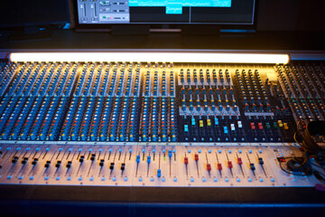 Close-up of professional audio mixing console with computer in digital recording studio