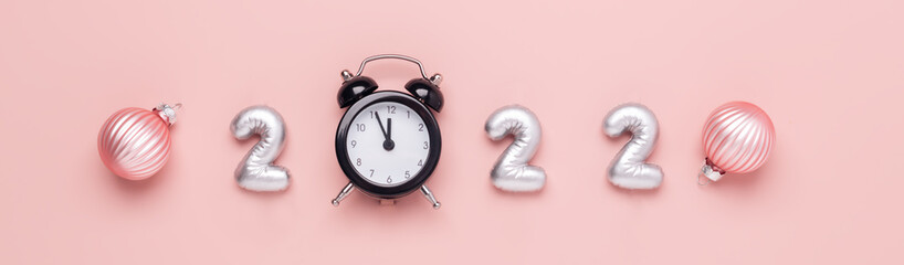New year composition with silver numbers 2022 and black alarm clock on pink background. Happy New Year concepts
