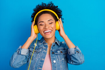 Photo of cool happy young woman wear headset enjoy music isolated on blue color background