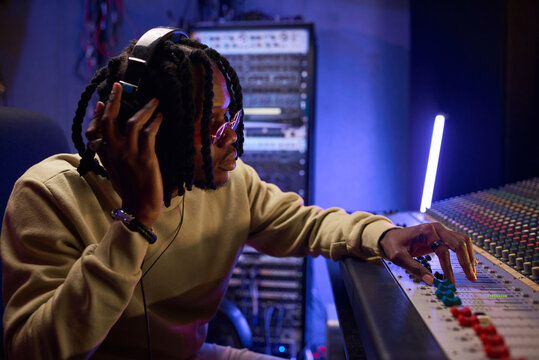 Male music arranger composing song on midi piano and audio equipment in digital recording studio