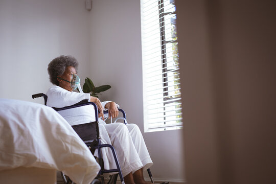African american senior woman sitting on wheelchair with oxygen mask at home