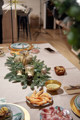 table decorated with Christmas ornaments prepared for family Christmas Eve dinner. Assorted canapes, Iberian ham and prawns. tradition and family reunion concept