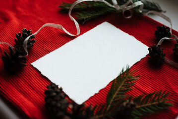 Christmas invitation set with card mockups. Paper blank, fir tree branches, cones on a red background.Christmas, winter, new year concept