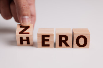 Hand flip wood cube change the word Zero or Hero concept.