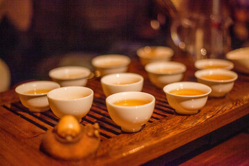 Photo of white cups with tea on a brown wooden tray in a cafe