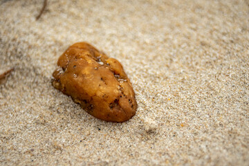 Large orange pebble rests in the sand