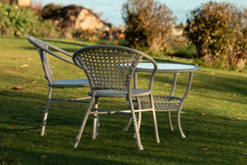 Wicker garden furniture in a green meadow by the sea. Plastic furniture