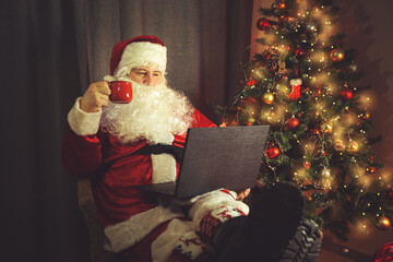 Authentic Santa Claus is working on a laptop.