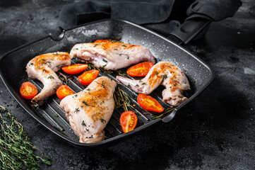 Roasted rabbit legs in a pan with thyme. Black background. Top view